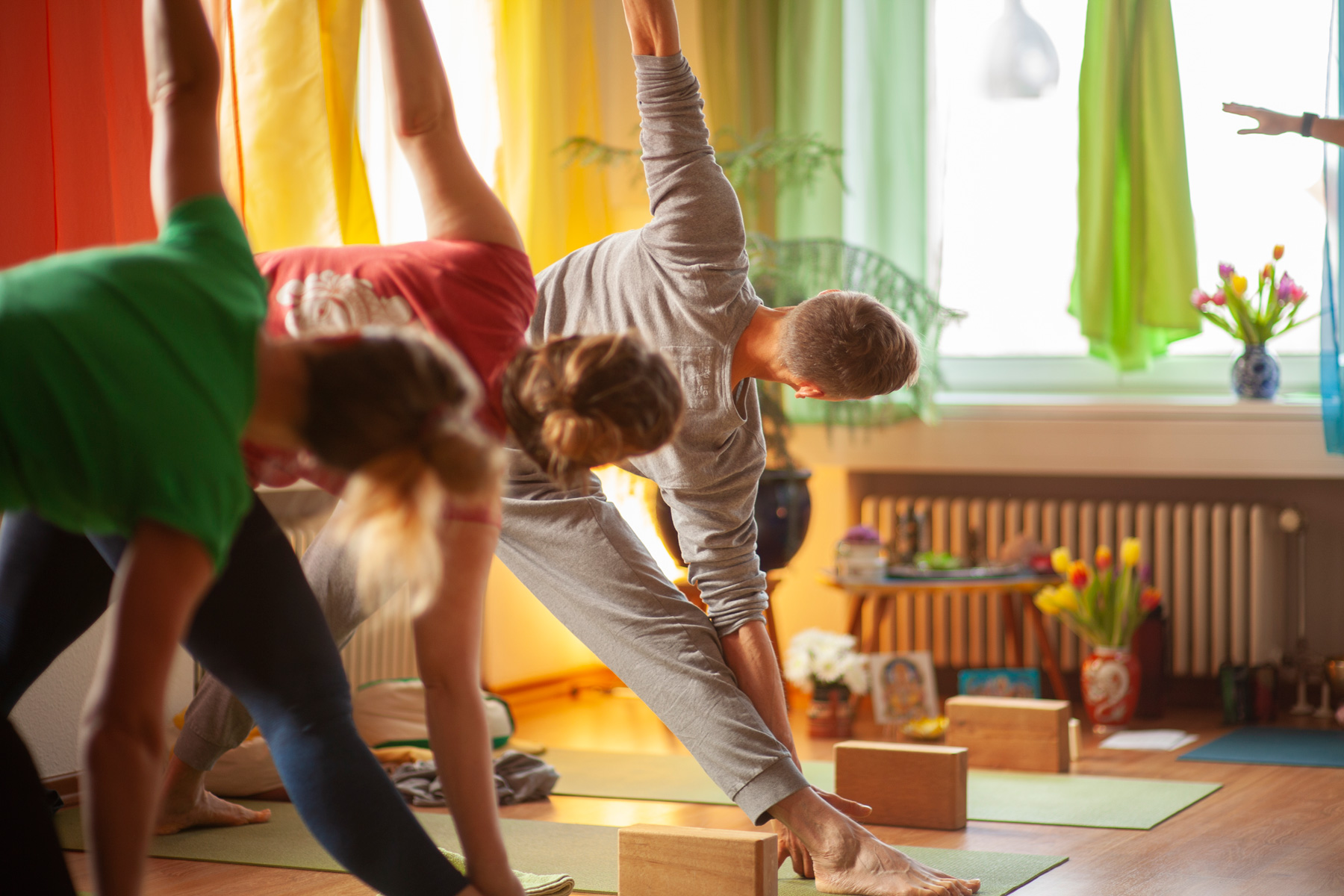 Yoga-Schüler:innen üben das Dreieck (Trikonasana) während eine Business-Yoga - Einhet